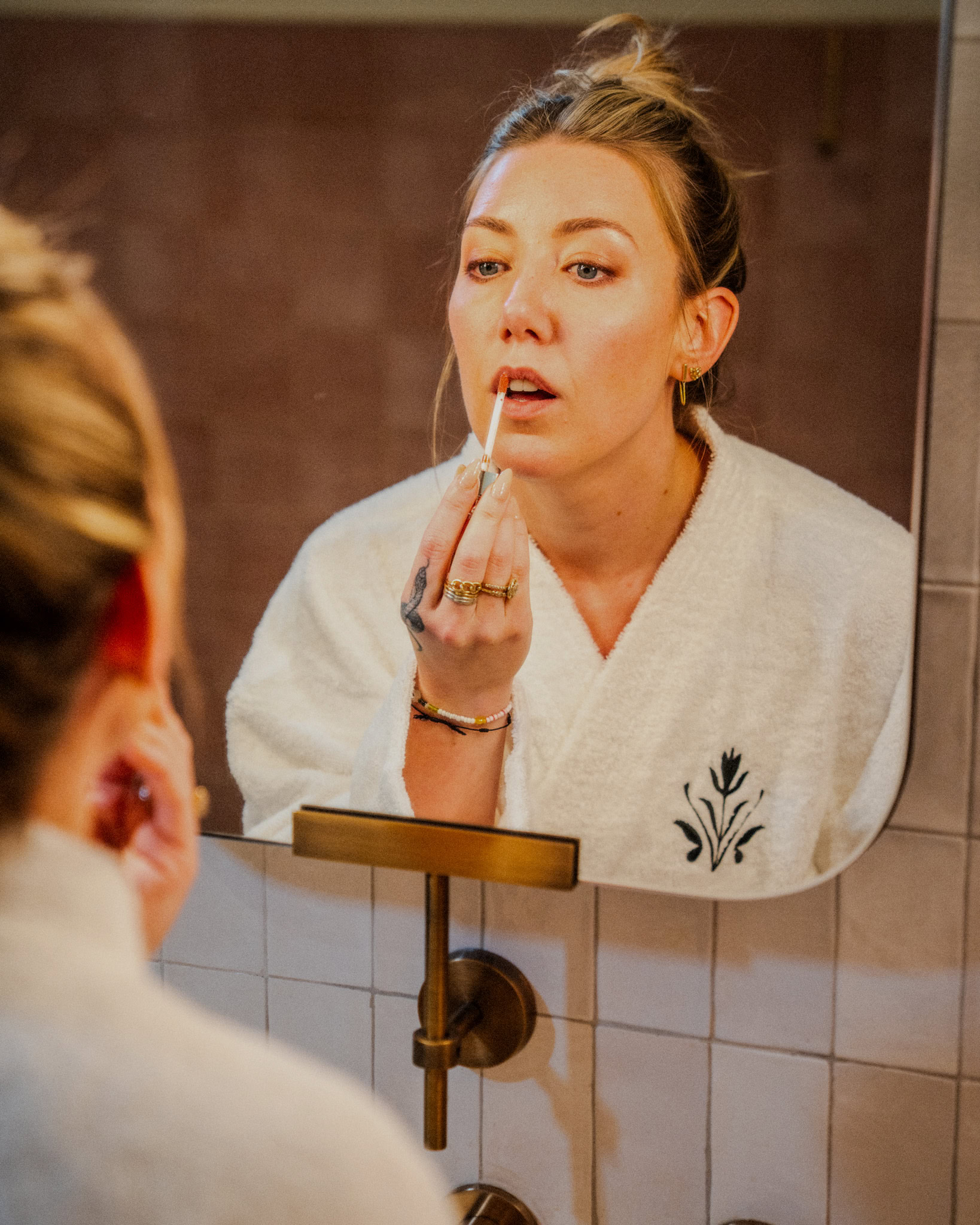 Woman applying lip balm while looking in bathroom mirror